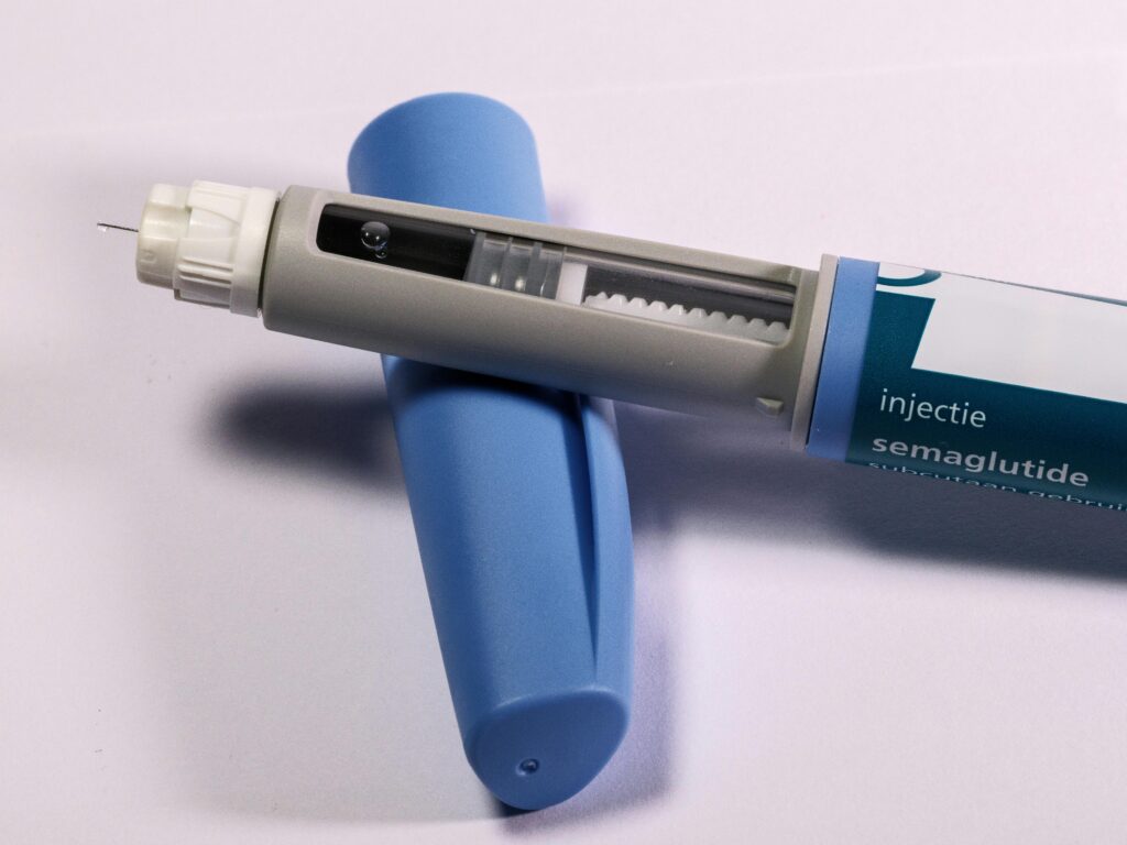 Semaglutide injection pen with needle exposed, resting on packaging