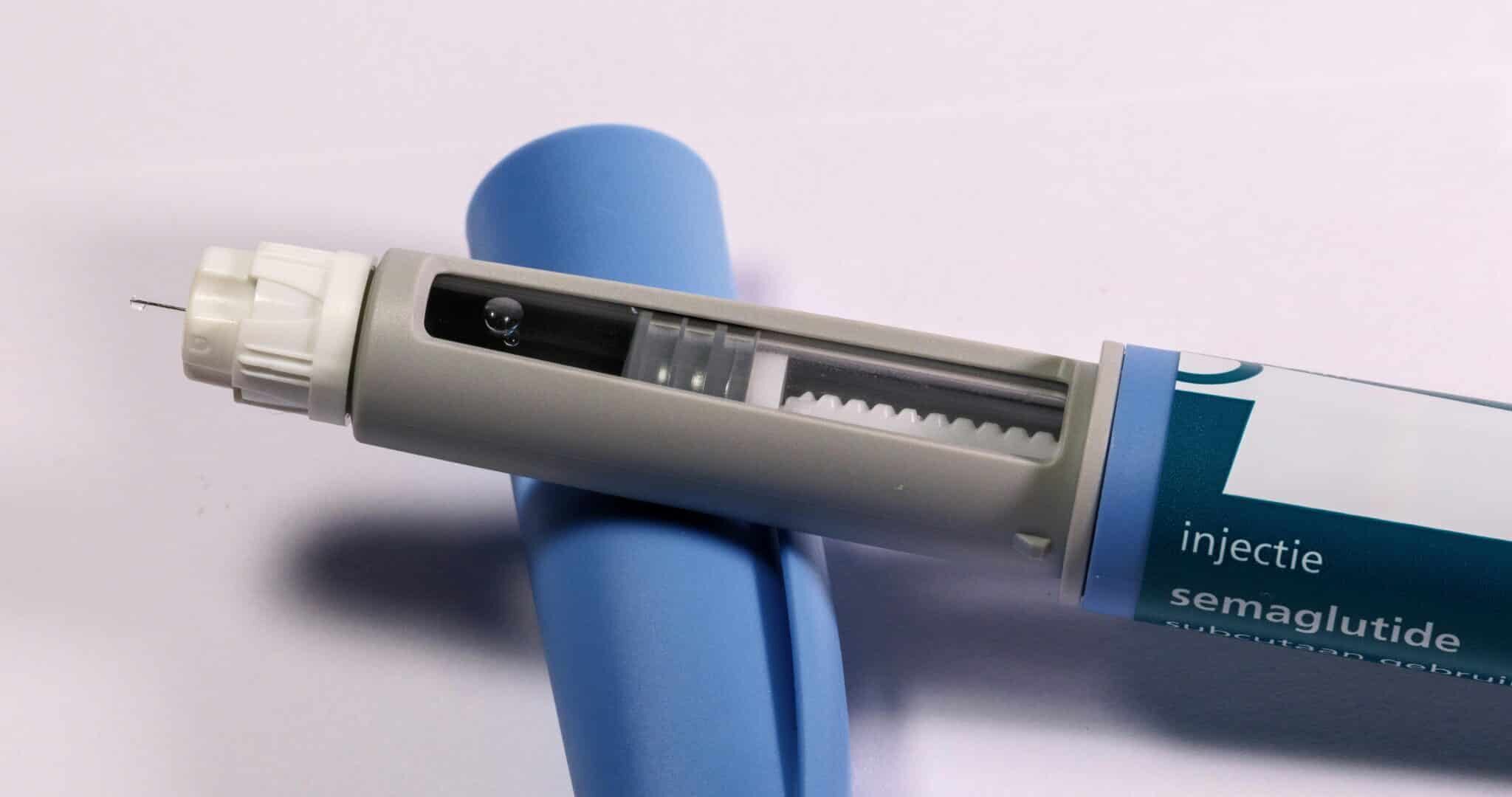 Semaglutide injection pen with needle exposed, resting on packaging