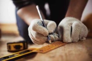 Person wearing gloves measuring wood