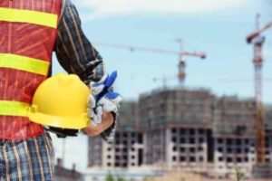 Construction worker on a job site holding a yellow hard hat