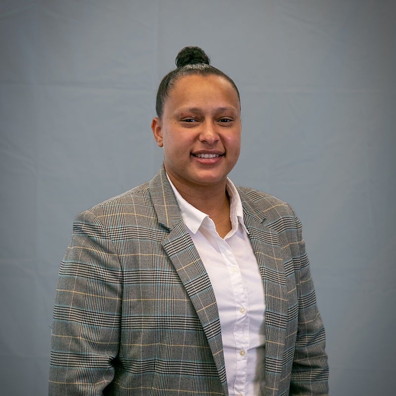 Professional headshot of Faith Deredge, Esq., smiling, wearing a gray plaid blazer over a white shirt, against a gray background.