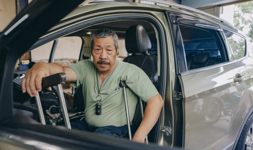 Elder man injured in a car accident using crutches.