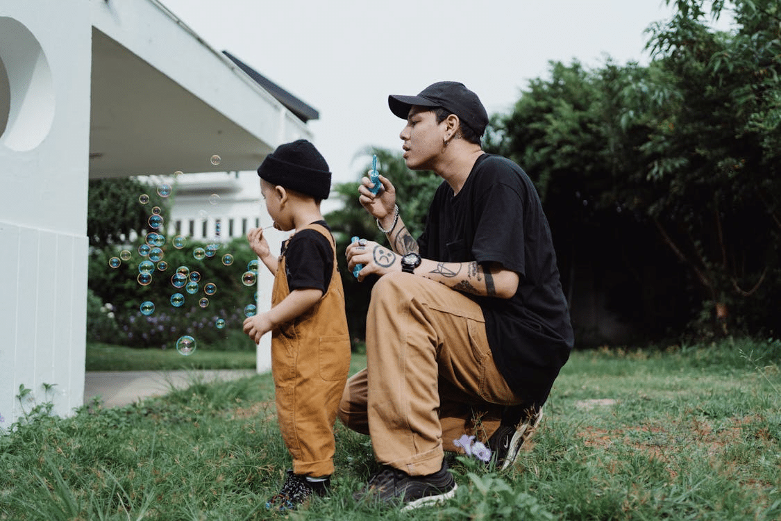 Man and young child blowing bubbles together in backyard