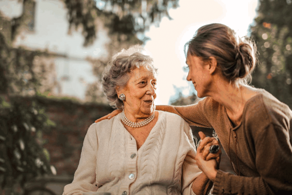 Older woman and younger woman smiling together outdoors, holding hands