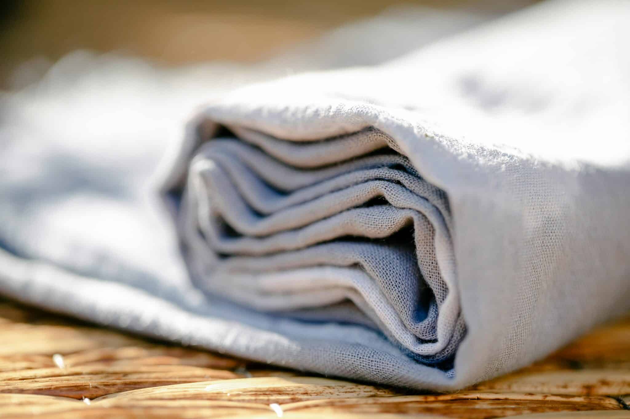 Folded white linen fabric, close-up on woven surface