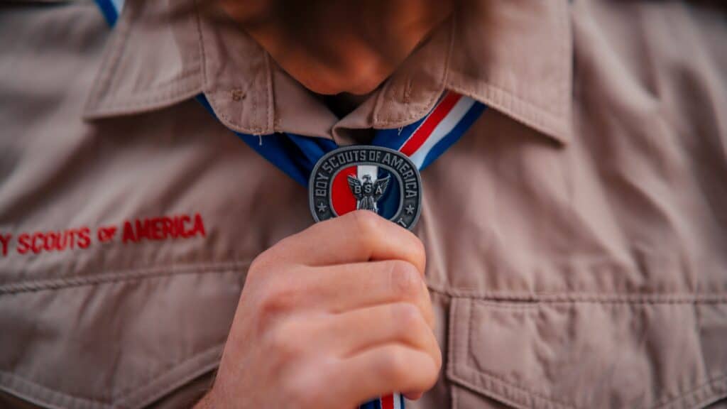 Boy Scout holding Eagle Scout medal on ribbon, wearing uniform