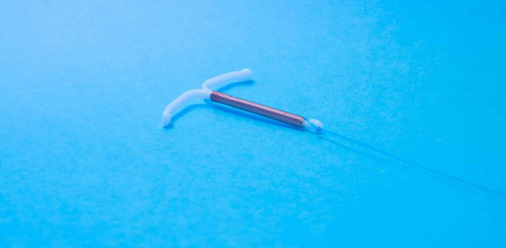 Copper IUD device on blue background