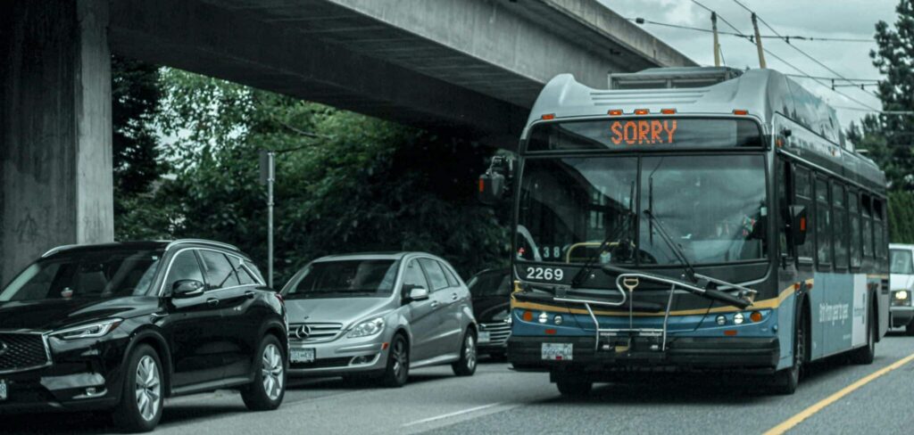 City bus displaying 'Sorry' sign, stopped in traffic under overpass