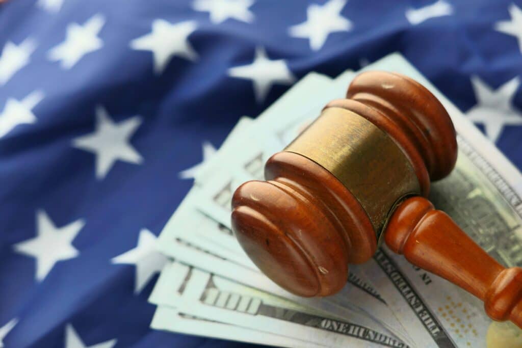 Wooden gavel resting on cash and American flag