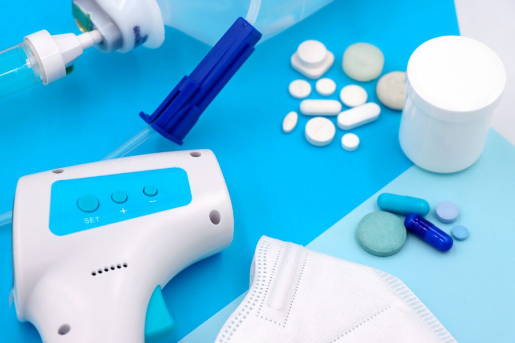 Pastillas variadas, dispositivo médico y mascarilla facial sobre fondo azul