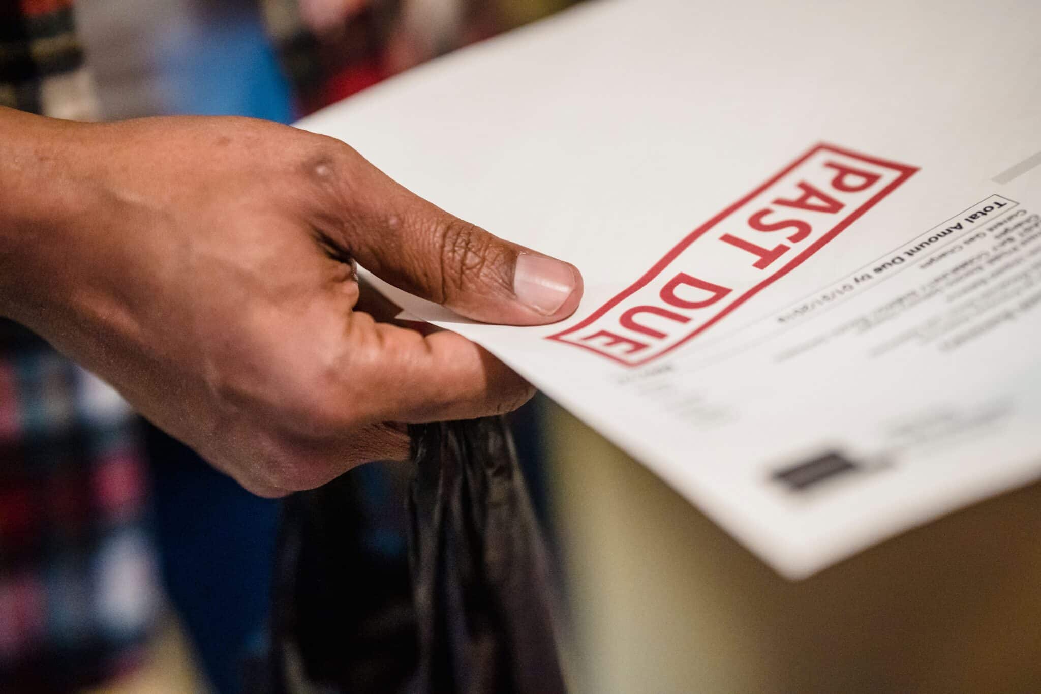 Hand holding invoice stamped "PAST DUE" in red.